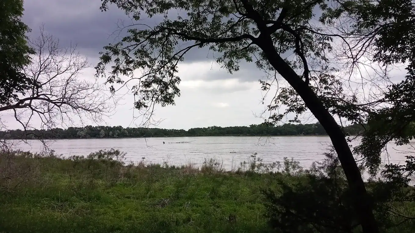 Lake view at Homestead Presbytery with trees and cloudy sky.